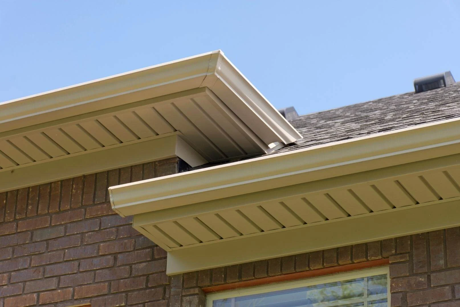 House eaves with soffit panels beneath a shingle roof