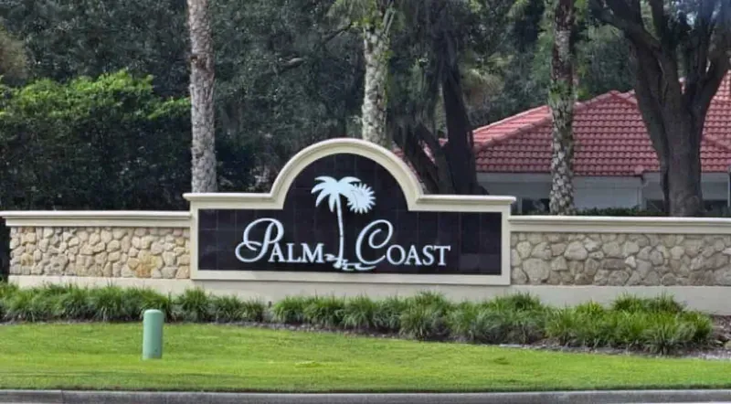 Palm Coast, Florida welcome sign with tile-roofed homes behind it